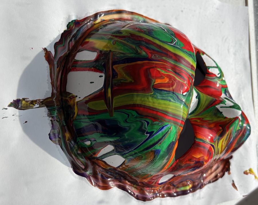 A marbled paint-poured mask drying in the sun